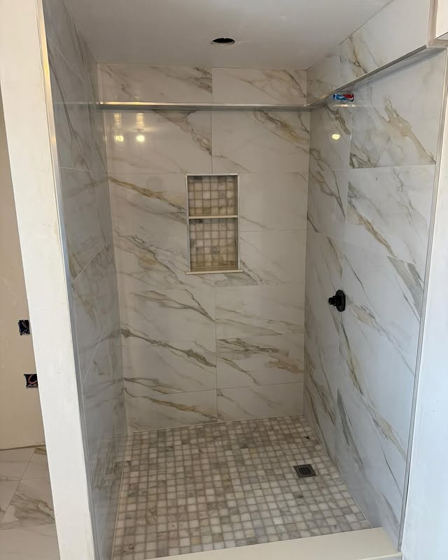 Calacatta marble walk-in shower with mosaic floor and recessed niche installed by Dynamic Tile